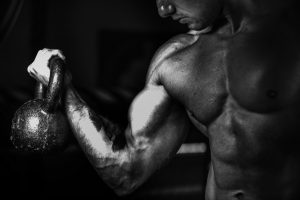 strong muscular man lifts kettle bell